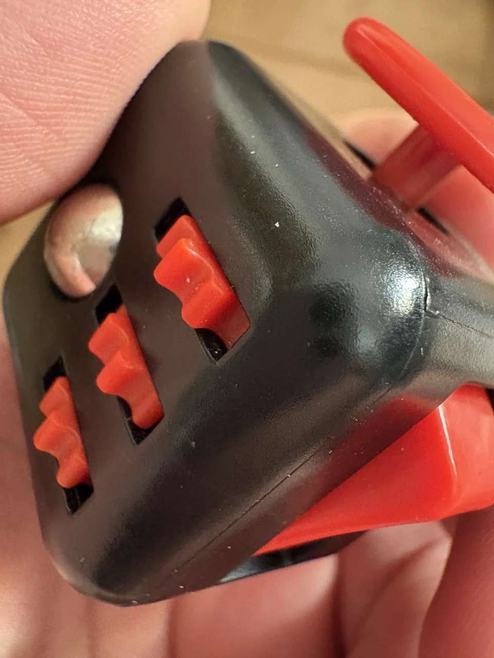 Una mano sujetando un dispositivo negro con controles rojos